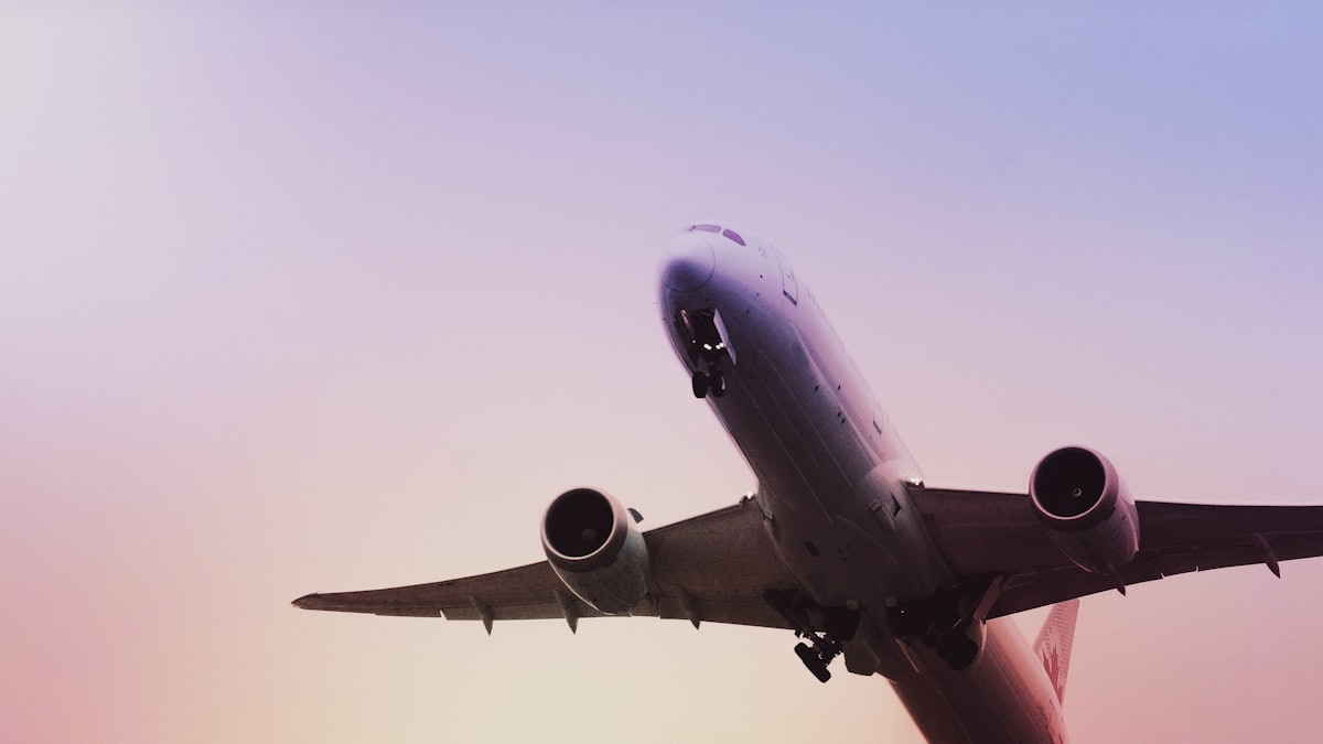 Plane taking off into a pink sky